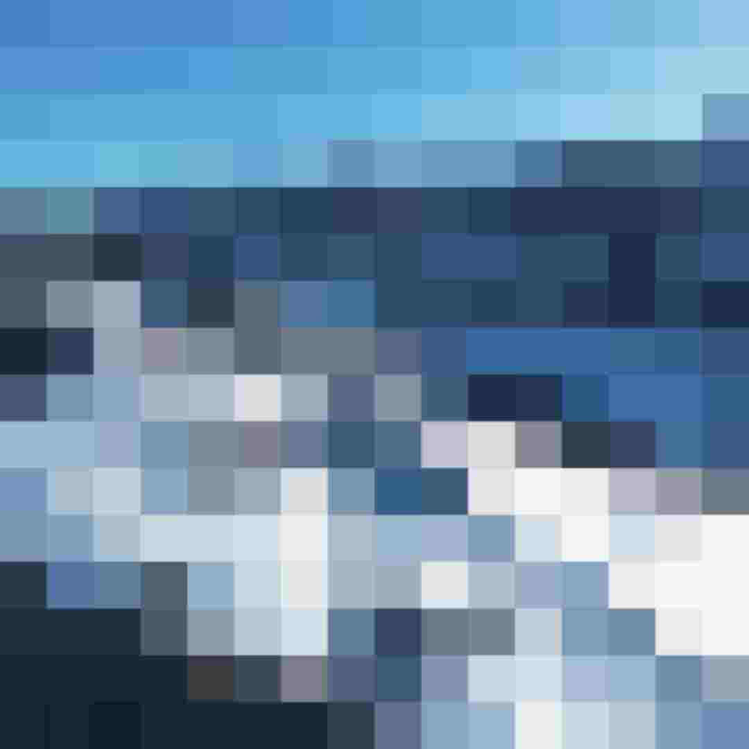 Verschneites Bergdorf in weiter Winterlandschaft mit umliegenden Bergen und einzelnen Häusern im Tal